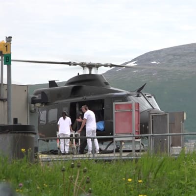 En helikopter har landat vid ett sjukhus, två sjukvårdare rullar bort en bår.