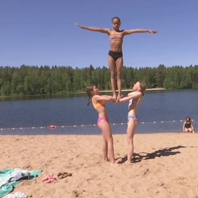 Kolme tyttöä rakentaa ihmispyramidia hiekkarannalla. Tytöt ovat ylinnä Jade Marttila, ja alhaalla vasemmalla Kerttu Laasanen  ja oikealla Sonja Suomalainen.