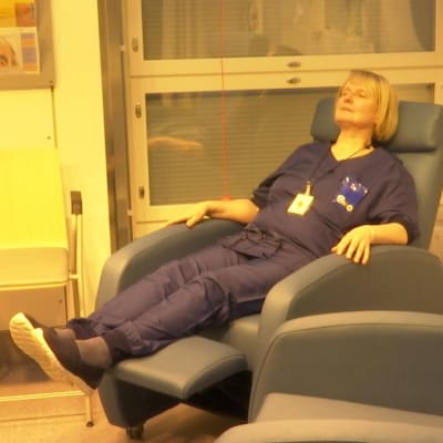 Nainen istuu tuolissa keltaisessa valossa keskussairaalan päivänvalohuoneessa 