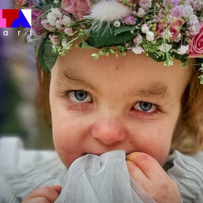 Kusivuotias erityislapsi Hilda Tolonen katsoo kameraan kukkaseppele päässään.