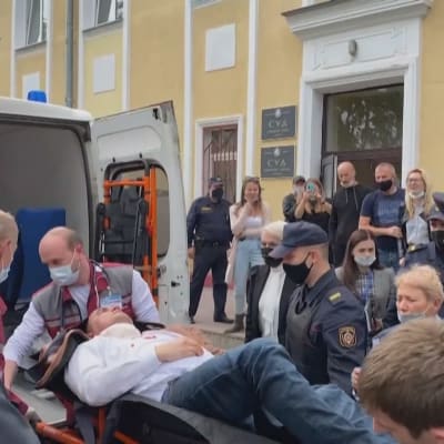 Stepan Latypov på en bår i mitten. Akutvårdare och poliser står omkring honom.