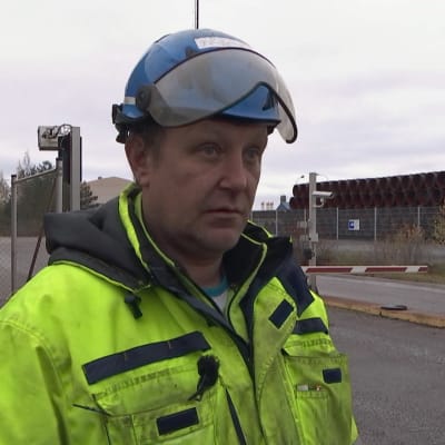 Lars Westerholm står i skyddshjälm och overall framför porten till hamnen i Lappvik. 