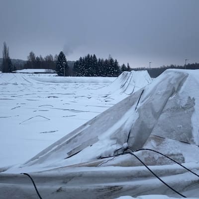Lumen alta pilkistää romahtaneen kuplahallin rakenteita ja kangas kentän päällä