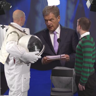 Presidentti Niinistö katsoo astronauttipukuista miestä.
