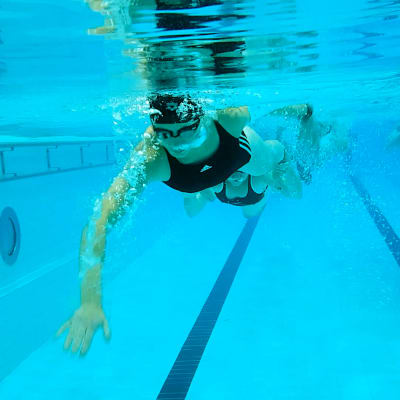 Simmare fotograferade under vattenytan i simhall. 