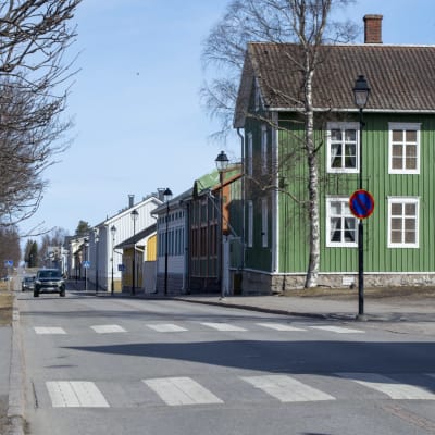 En bild på gamla stan i Brahestad. På bilden syns en väg och några bilar samt ett grönt trähus med vita fönster.