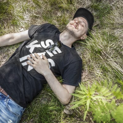 Mikko Toiviainen makaa selällään metsässä ja hymyilee silmät kiinni.