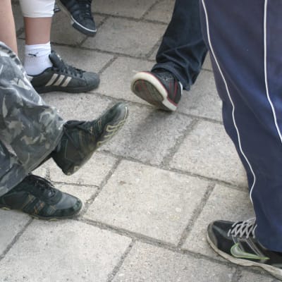 Ungdomar som står i en klunga, man ser deras ben och skor.