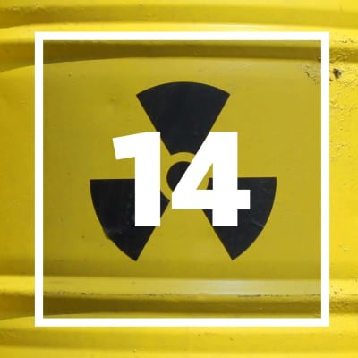 En ruta med siffran 14, i bakgrunden gula tunnor med radioaktivitetssymbol.
