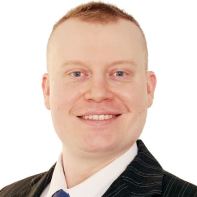 Kasvokuva Teemu Torssosesta. Hän hymyilee ja katsoo kameraan. Valkoinen tausta.
