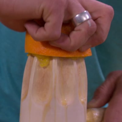 Jim pressar saften ur en apelsin på citruspressen av björk.