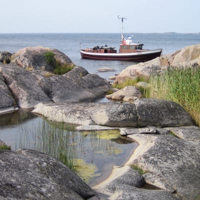 Kallioinen merenranta ja vene.