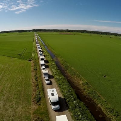 Asuntoautoja jonossa Suviseuroihin pienellä peltotiellä.