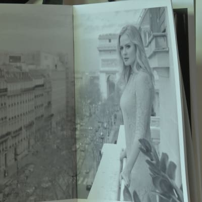 En kvinna i spetsklänning står på en balkong i Paris.