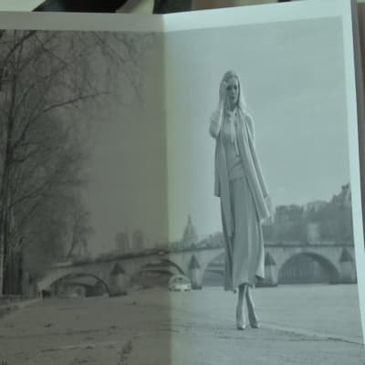 En kvinna i kjol och tröja går vid Seine i Paris.