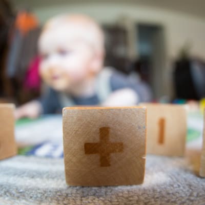 Lasten rakennuspalikoita, joiden takaa näkyy vauva.