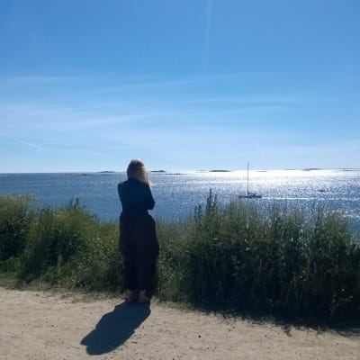 Nainen tuijottaa merelle.