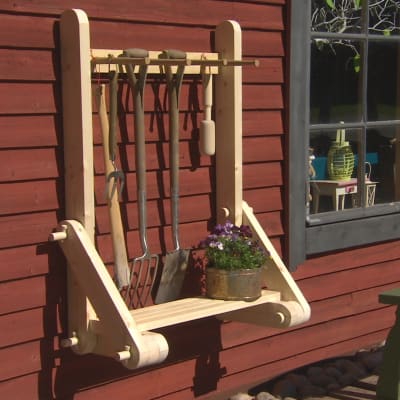 En ställning för trädgårdsredskap på en röd vägg