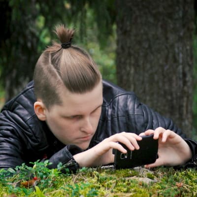 Hanna Bäckström fotograferar med sin mobil ute i skogen.