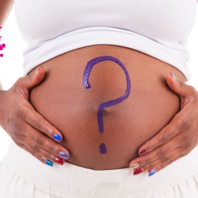 en gravid vuxen kvinna som står mot en vit bakgrund, har sina händer på sin mage var det är målat ett lila frågetecken