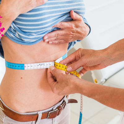 en flicka som är hos en doktor som mäter hennes midja med ett måttband