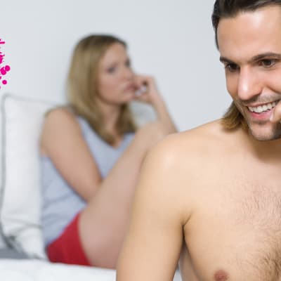 en man och kvinna som sitter i sängen, mannen talar i telefon och kvinnan ser sur ut