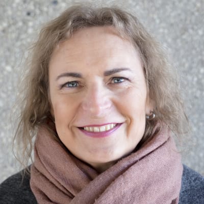 Tiia Kovanen katsoo suoraan kameraan ja hymyilee.
