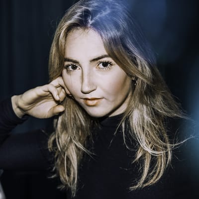 Laulaja Erika Sirolan lähikuva. Nojaa tikkaisiin.