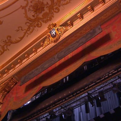 En röd ridå är uppdragen på Åbo Svenska Teater, bitar av det gulddekorerade taket på teatern.