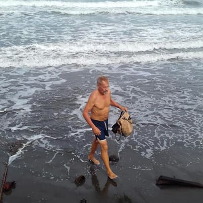 Simo Aaltonen kävelee rannalla ja kerää roskaa