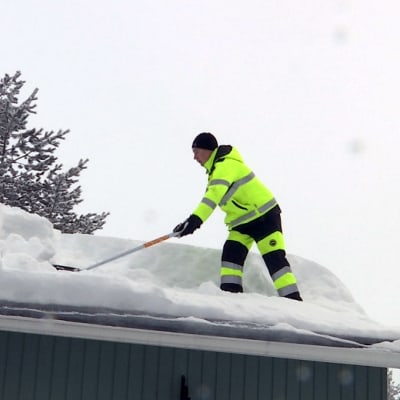 Mies kolaa lunta katolla