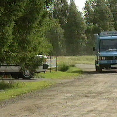 Vaaleansininen jäätelöauto ajaa hiekkatiellä 1995.