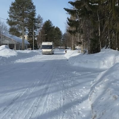 Matkailuauto ajaa lumisella Kuusamon Punaisentorintiellä.