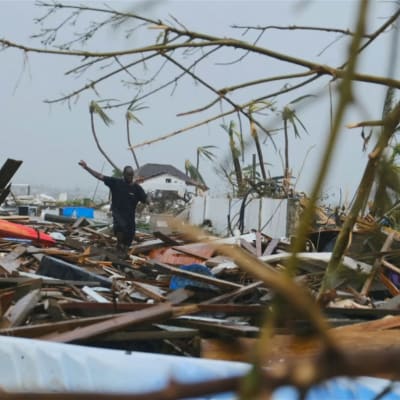 En man går över en massa bråte på Bahamas där orkanen Dorian dragit fram.