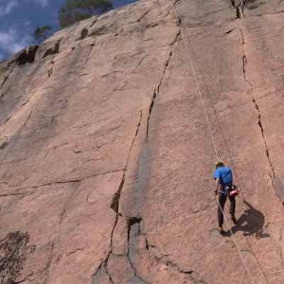Timo Toivanen firar ner sig för bergväggen i Olahava, Repovesi nationalpark.