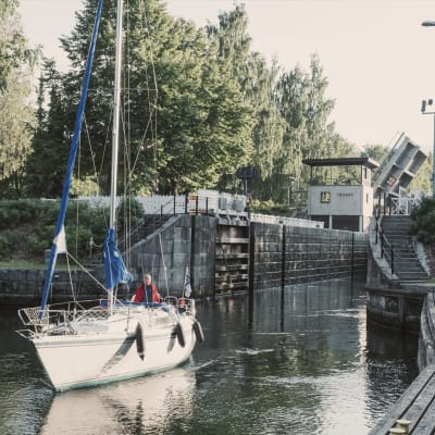 Segelbåt har precis kommit ut ur Vääksy kanal, kanalmynningen i bakgrunden.