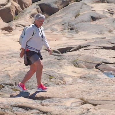 Kvinna går på släta klippor.