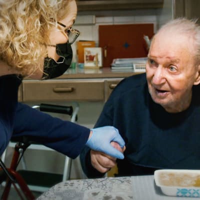 En närvårdare håller sin hand på en patient.