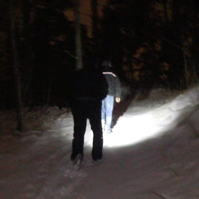 Två personer går i en mörk skog.