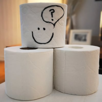 toalettpappersrullar på ett bord - en har en smiley ritad på sig