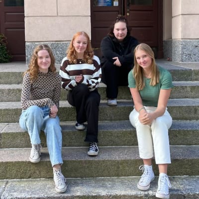 Bianca Vuorenmaa Närvä, Victoria Kärkinen, Saara Manni och Iréne Heikius sittande på en trappa. 