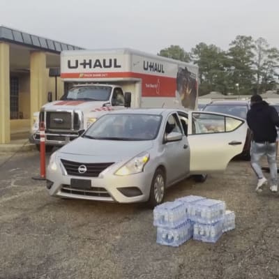 En person laddar vattenflaskor i en bil.