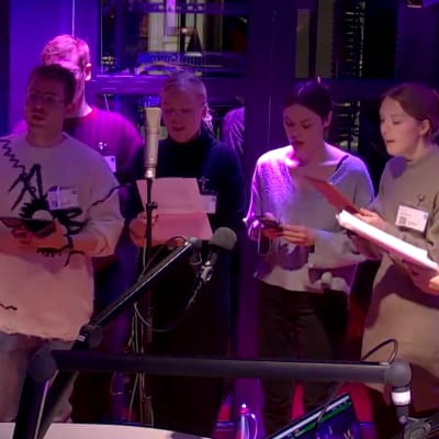 Fyra män och fyra kvinnor i en kör står uppställda och sjunger i en radiostudio.