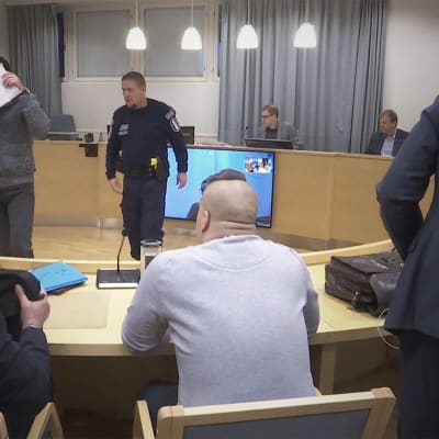 Käräjäoikeuden istuntosalissa syytettyjä ja asianajajia.