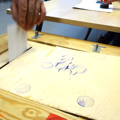 Käsi laittaa vaalilippua uurnaan.