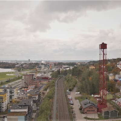 Punainen haulitorni korkealla, alhaalla maisema Tampereesta. 