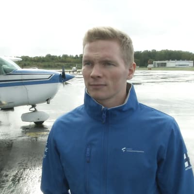 Gymnasten Tomi Tuuha står bredvid ett flygplan