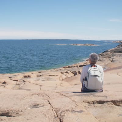 Kvinna tittar ut mot horisonen på Åland