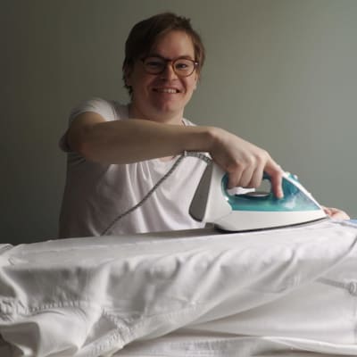 Elias Poutanen ler och stryker sin skjorta
