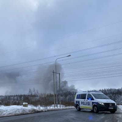 Poliisiauto tiesululla, tulipalon savua taustalla